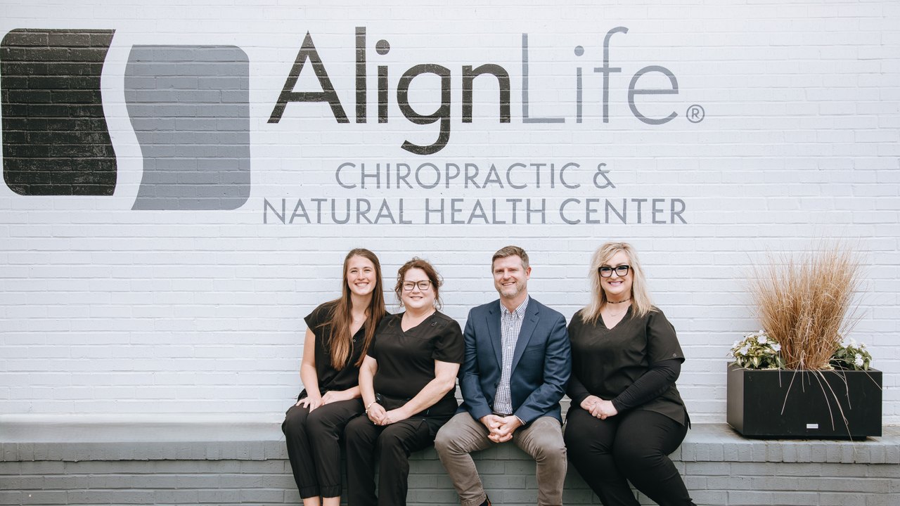 AlignLife Tryon team seated in front of the AlignLife Chiropractic and Natural Health Center sign
